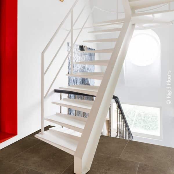 Escalier flottant blanc contemporain au-dessus d'un carrelage grand format brun foncé. Murs blancs lumineux avec niche rouge et tableau.