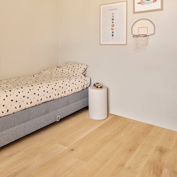 Chambre d'enfant aux murs clairs, lit simple gris, parure de lit à motifs. Cadres Système Solaire et escargot-fusée, mini panier de basket mural.