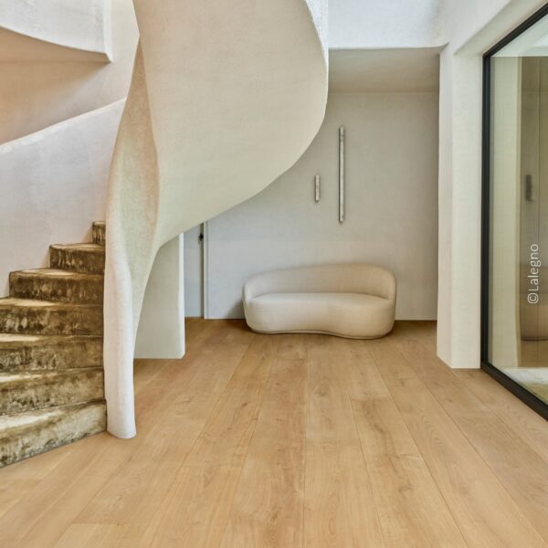 Escalier colimaçon texturé et banquette minimaliste dans un hall moderne. Plancher en chêne clair et murs blancs organiques.