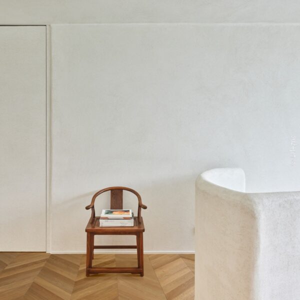 Intérieur minimaliste: chaise chinoise bois, mur texturé blanc, parquet chevron. Élément courbe. Copyright LaLegno.