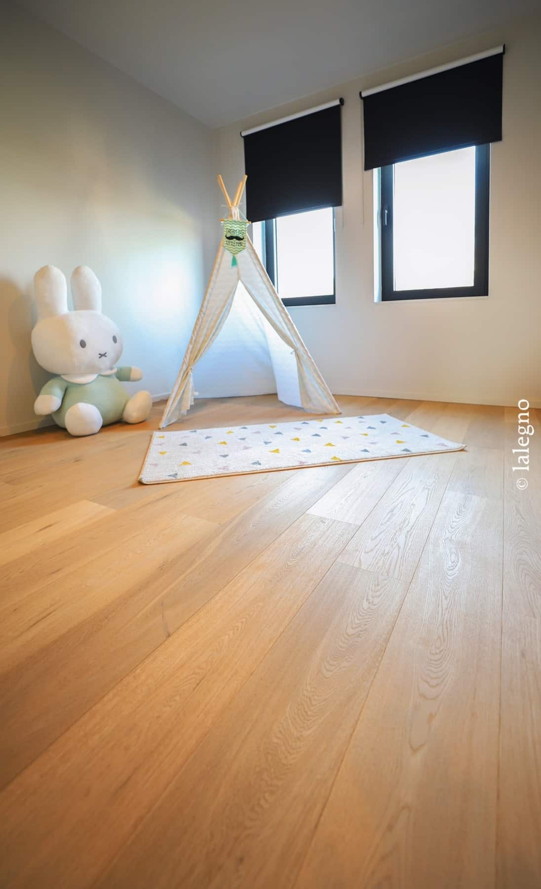 Chambre d'enfant lumineuse: plancher chêne clair, tipi beige sur un tapis coloré, et grande peluche Lapin Miffy.