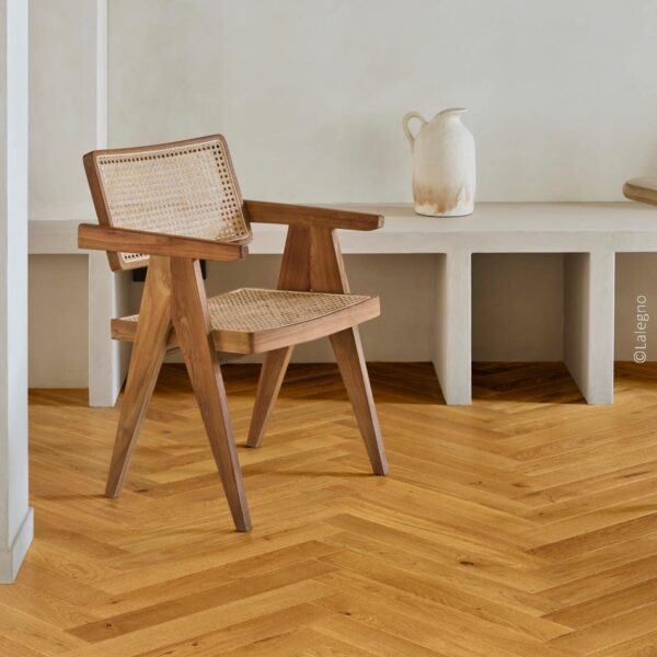Chaise en bois et cannage, design minimaliste, devant un banc en béton. Sol en parquet chêne clair posé en chevrons. © Lalegno.