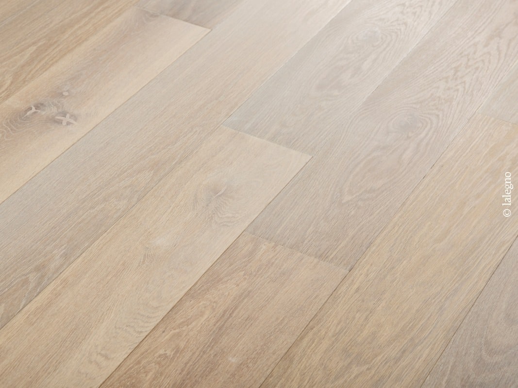 Plancher en chêne clair blanchi, lames larges posées en diagonale. Grain de bois texturé et nœuds naturels visibles. © lalegno.