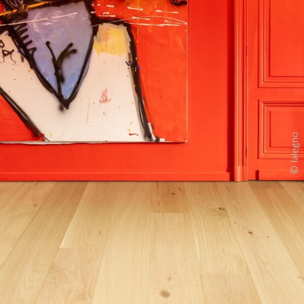 Parquet chêne clair devant un mur et une porte rouge vif. Le sol naturel contraste avec une grande toile d'art moderne expressive.