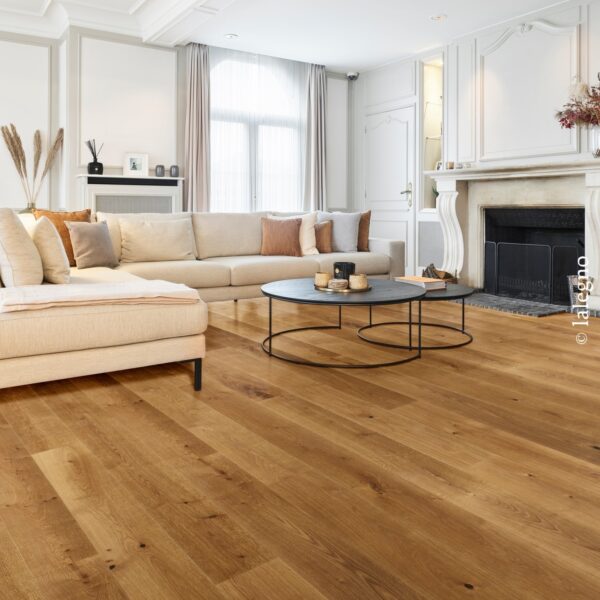 Salon chic et lumineux. Parquet chêne huilé, lames larges et rustiques, contrastant avec le canapé beige. Cheminées ornées et moulures.
