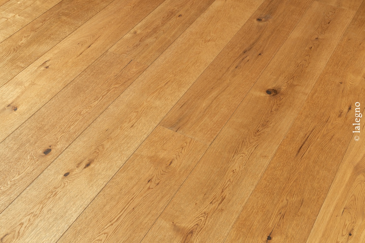 Lames de parquet en chêne massif rustique posées en diagonale. Teinte miel dorée avec nœuds marqués.