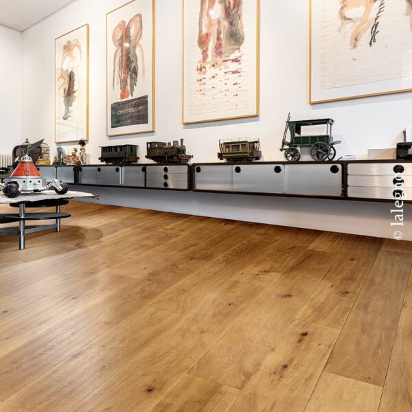 Parquet chêne doré en planches larges dans un intérieur moderne. Étagère flottante, jouets anciens, et grandes toiles abstraites encadrées.