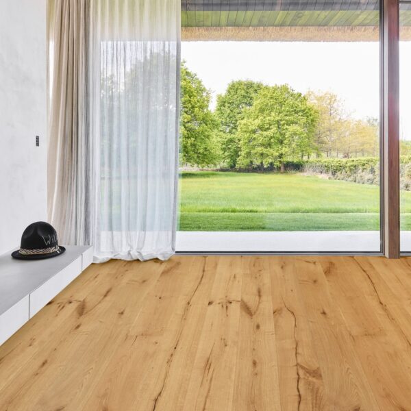 Parquet en chêne naturel rustique à lattes larges, fissures apparentes, baies vitrées et vue sur jardin. Plafond béton. Chapeau "Wild" sur console.