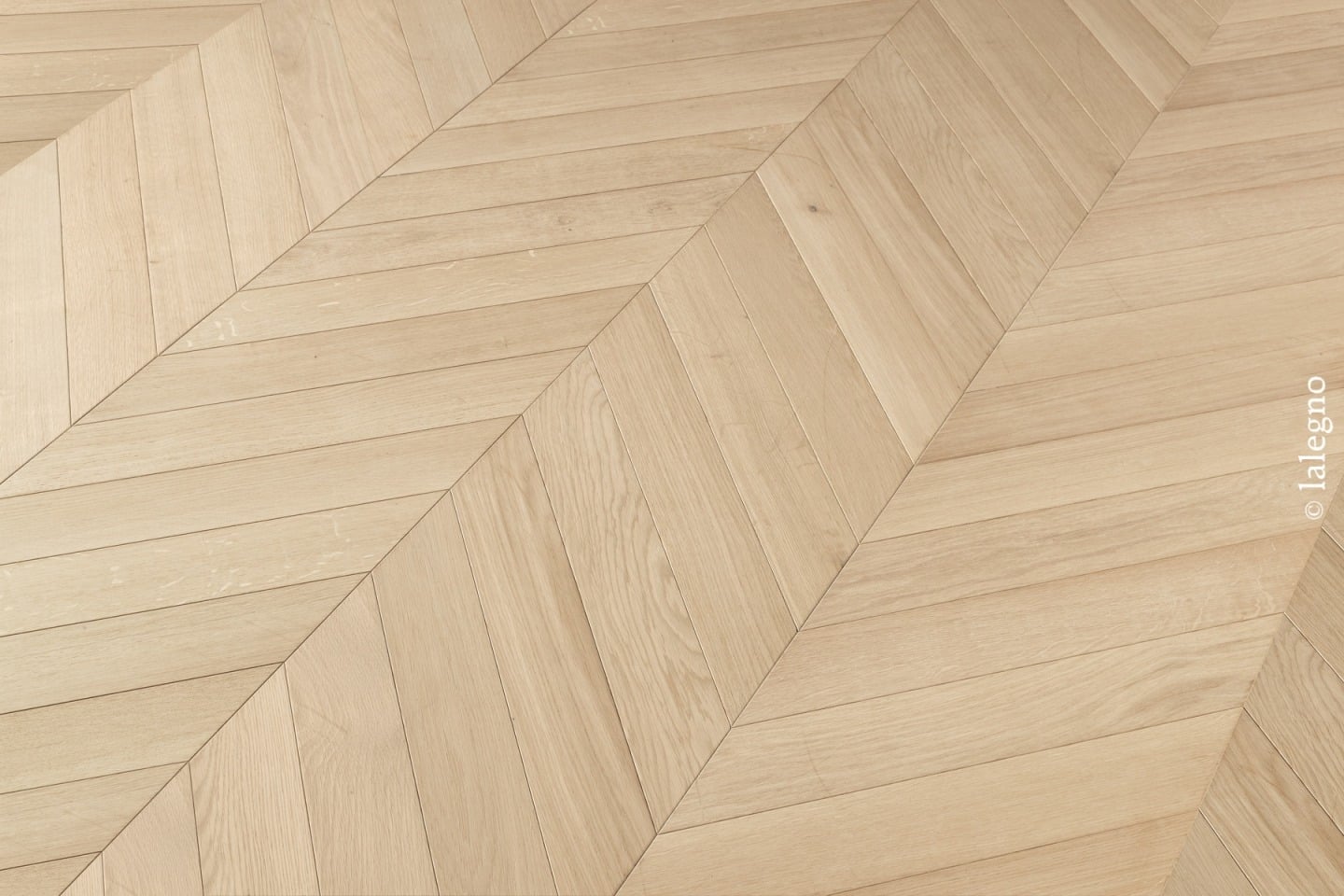 Parquet en bois de chêne clair, motif chevron moderne et net. Détail du grain de bois naturel. © lalegno.