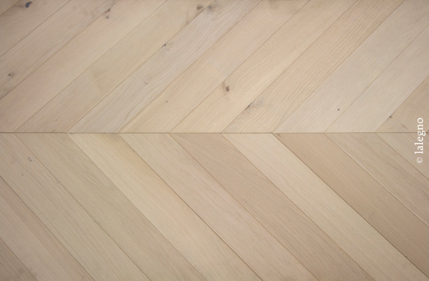 Parquet chevron en bois clair de chêne naturel, présentant un motif en V net avec grain visible. Copyright © lalegno.