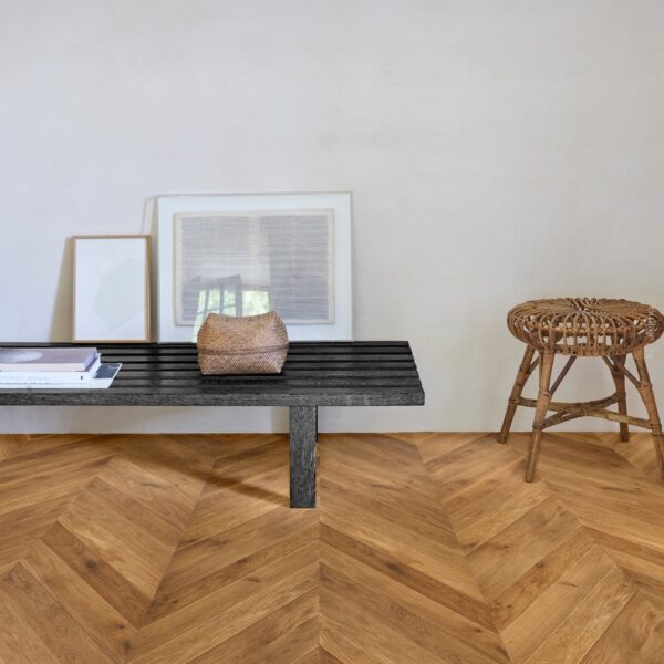 Parquet chevron chêne miel, banc noir minimaliste avec art encadré et tabouret rotin. Décoration intérieure naturelle et élégante.