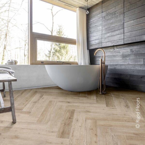 Baignoire moderne devant grande fenêtre, mur foncé et sol clair en chevrons chêne. Parquet Rigid Floors.