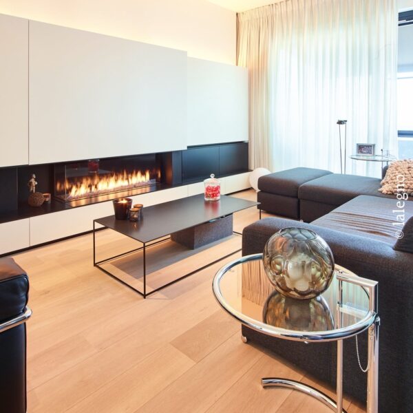 Salon minimaliste avec cheminée moderne horizontale et canapé gris sur plancher bois clair. Éclairage d'ambiance LED.