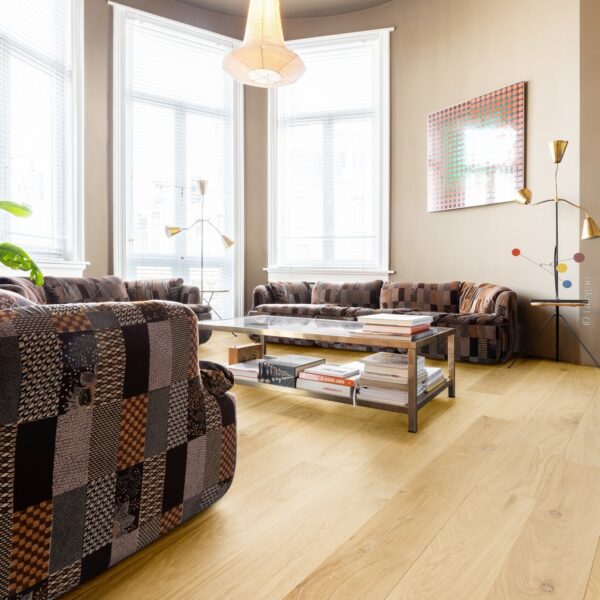 Intérieur de salon design. Parquet chêne clair, canapés patchwork et grande baie vitrée. Lustre en papier suspendu.