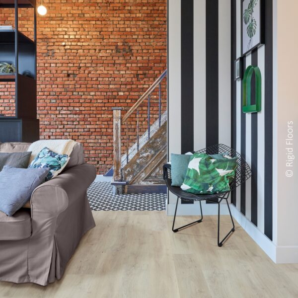 Sol LVT bois clair dans un salon éclectique. Mur de briques apparentes et mur à rayures audacieuses avec un escalier rustique.